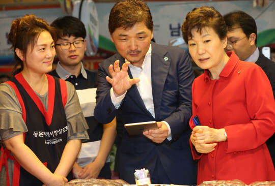 박근혜 대통령이 26일 제주 동문시장을 방문, 김범수 다음카카오 이사회 의장으로부터 ICT기술활용을 통한 전통시장 지원에 대해 설명을 듣고 있다.  사진= 연합뉴스